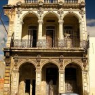 Vintage car parked in front of ornate two-story building with balconies and arches