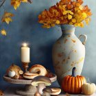 Autumn-themed still life with vase, pumpkins, mushrooms, and candle