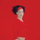 Woman with Red Headband and Blouse on Red Background