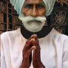 Elderly man in turban and white kurta with folded hands