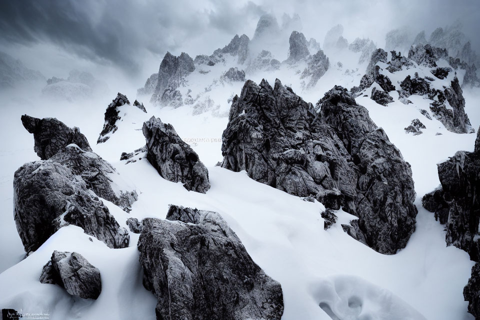 Monochrome mountain landscape with rugged rocks in snow under dramatic sky