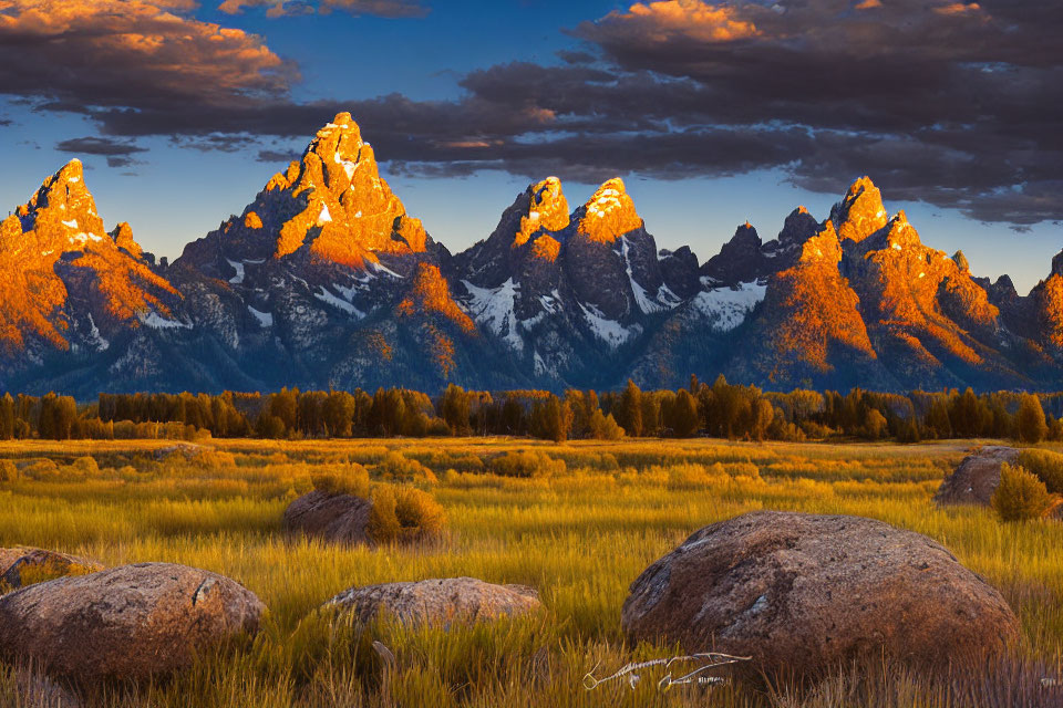 Scenic sunset over rugged mountain peaks and field with boulders