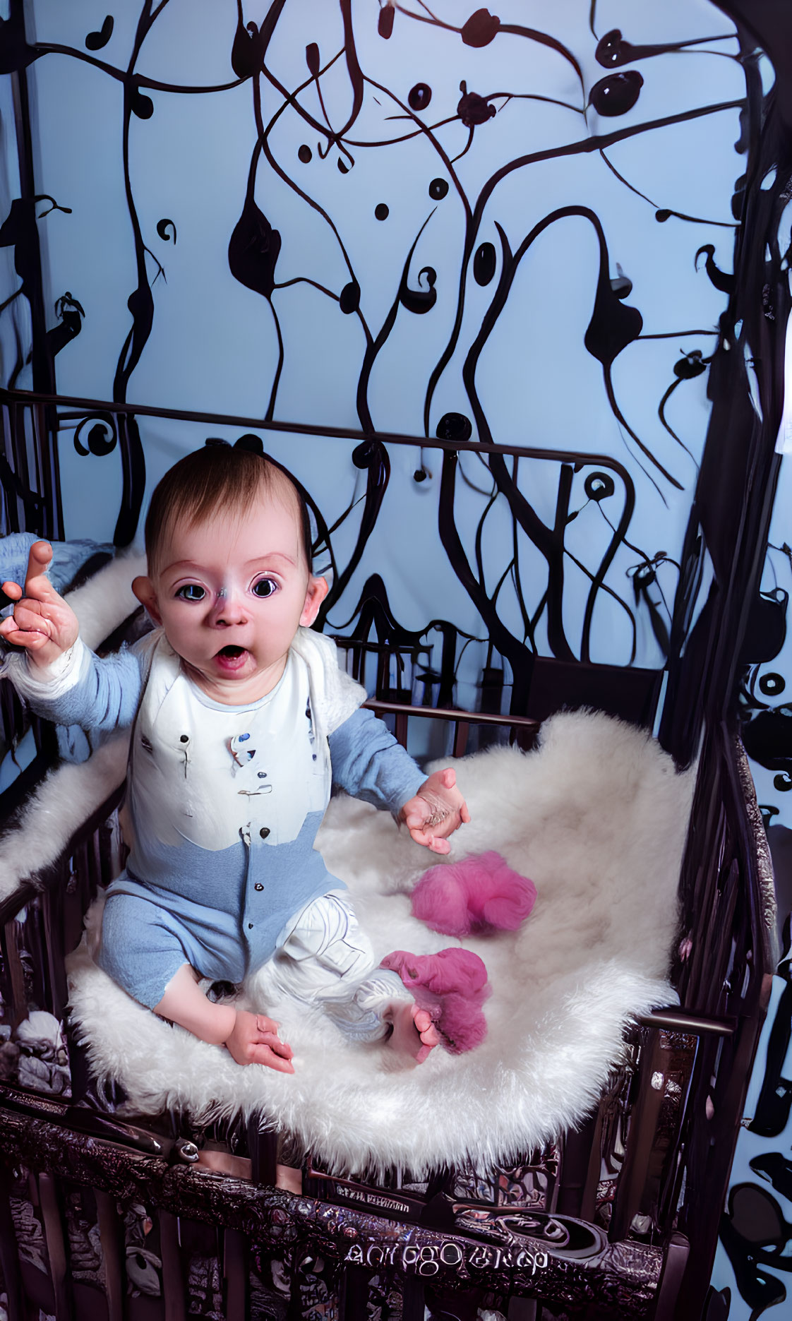 Wide-eyed baby in blue onesie in decorative crib with whimsical patterns