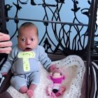 Baby in White Onesie Sitting in Yellow "T" Surrounded by Toys and Whimsical Wall