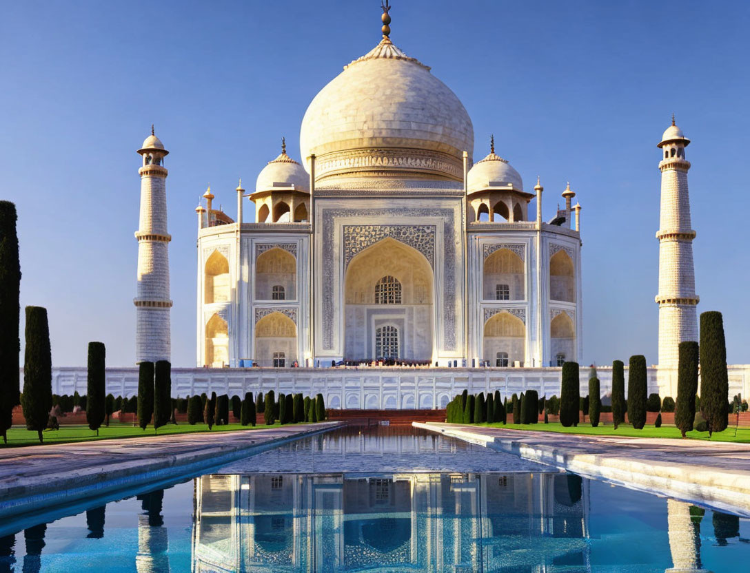 White marble Taj Mahal reflected in water under clear blue skies