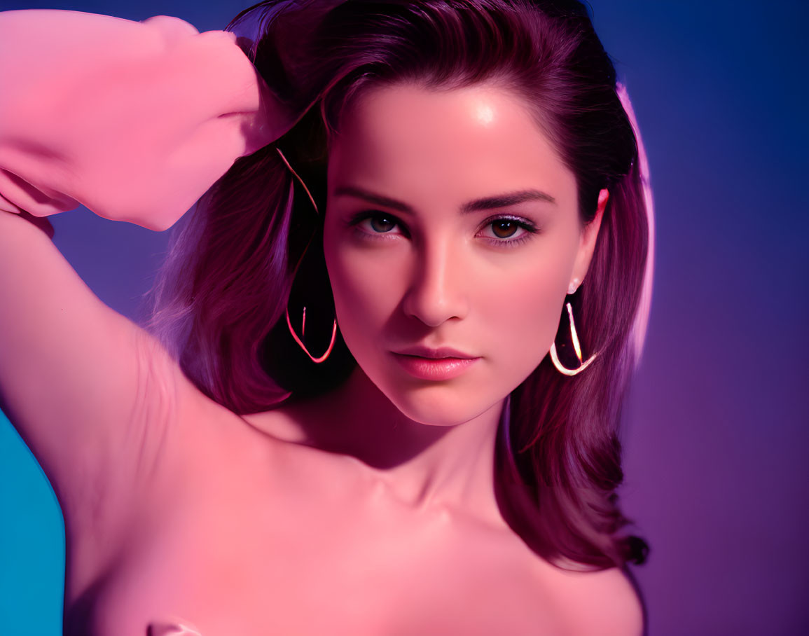 Portrait of Woman with Dark Hair in Pink and Blue Lighting, Hoop Earrings, Looking at Camera