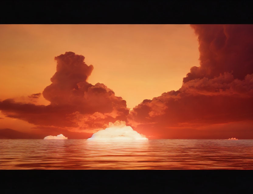 Vibrant orange sunset over ocean with fiery sky and cloud silhouettes