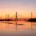 Tranquil twilight scene: golden trees, sailboat, floating leaves, hazy orange sky