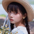 Braided hair woman in flower hat gazes back in floral setting