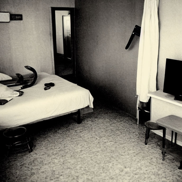 Monochrome hotel room with two beds, TV, chair, phone, and open door