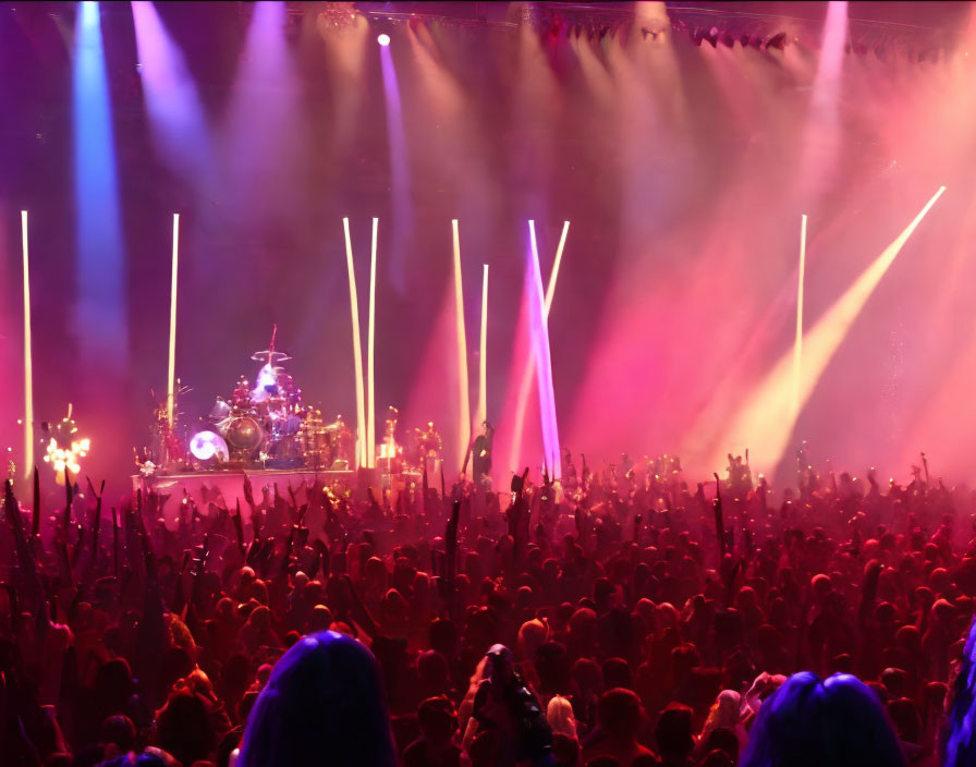 Vibrant concert scene with raised hands and drummer on stage