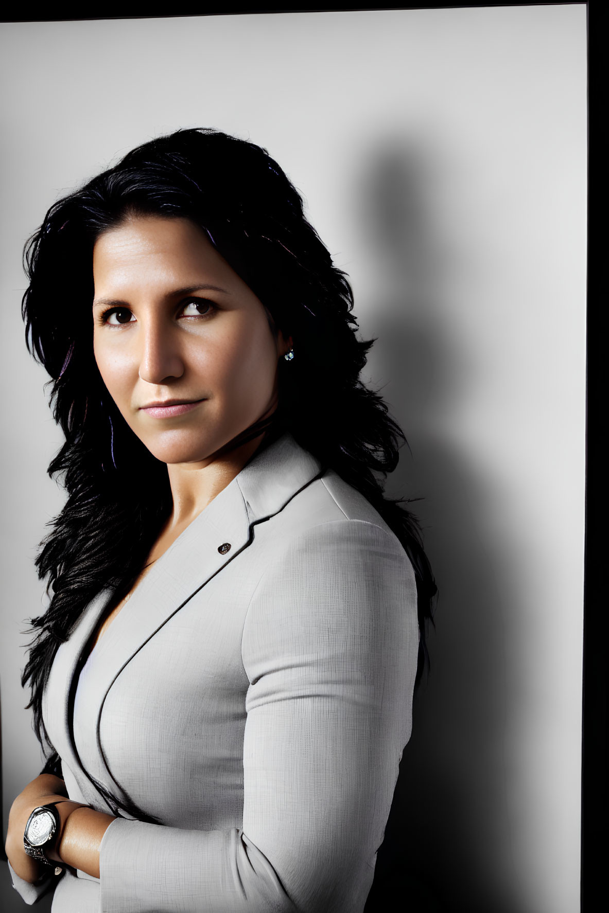 Serious professional woman in gray blazer with crossed arms