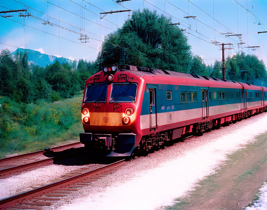 Electric train travels through lush green landscape on tracks