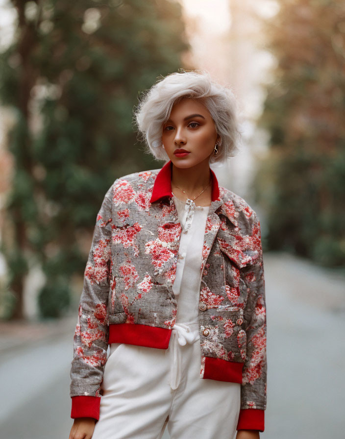 Silver-haired person in floral jacket and white pants posing outdoors