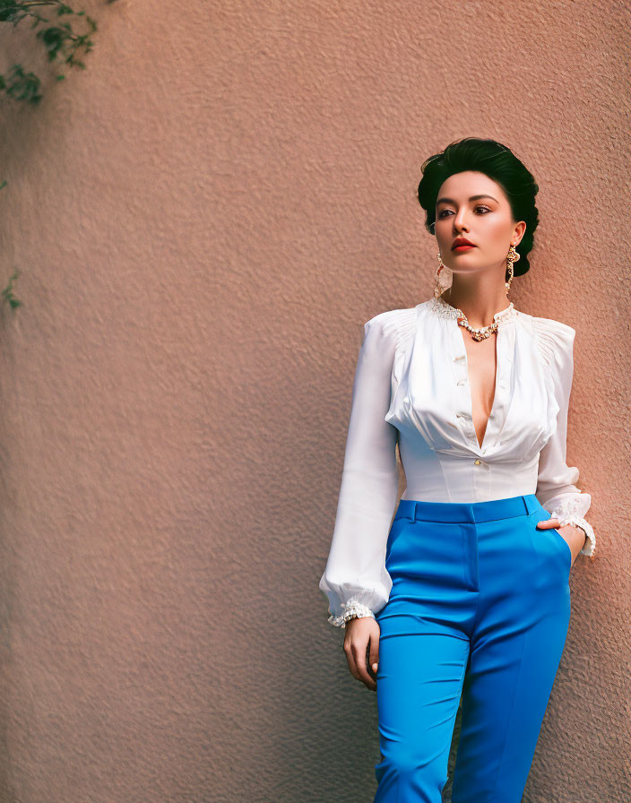 Stylish woman in white blouse and blue trousers against pink wall with ivy