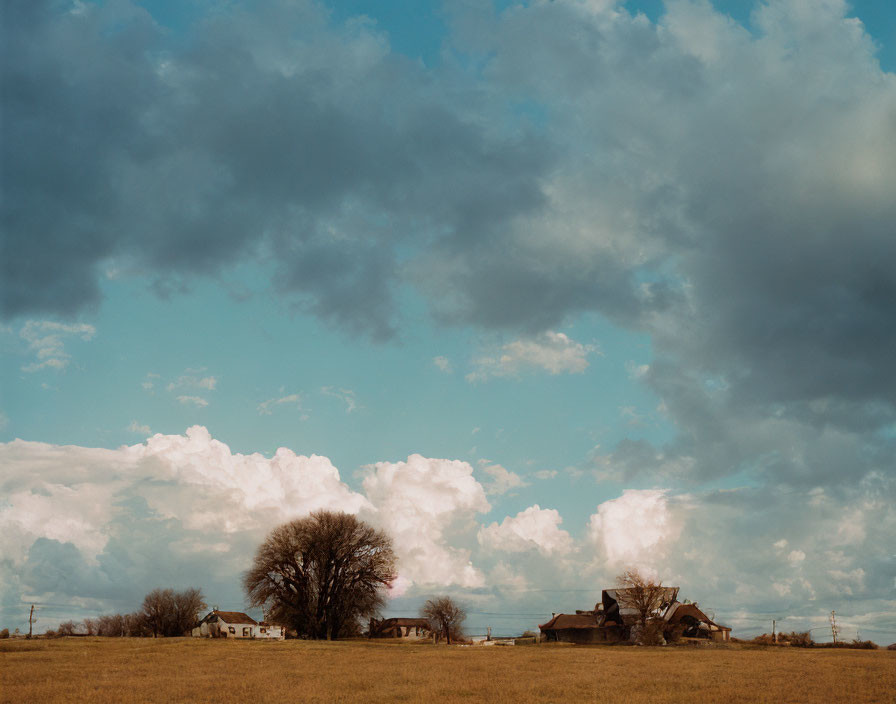 Expansive rural landscape with cloud-filled sky and houses.