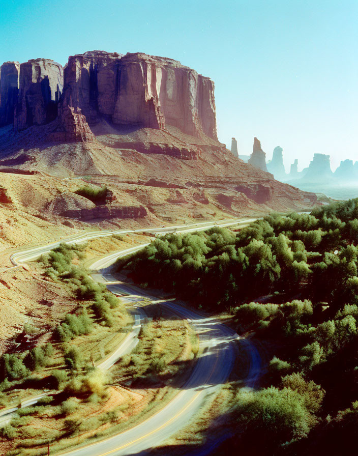 Scenic winding road through lush valley to red rock formations