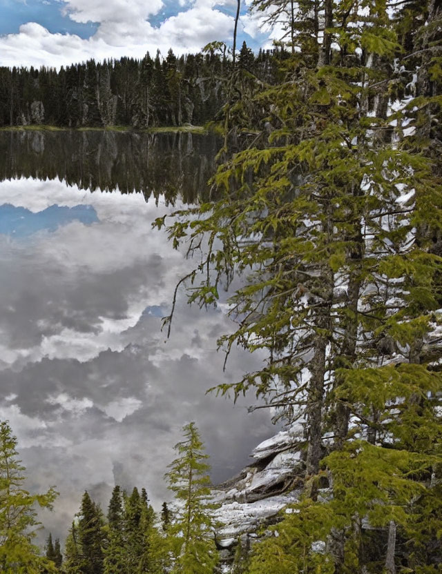 Tranquil lake with evergreen trees and snow patches