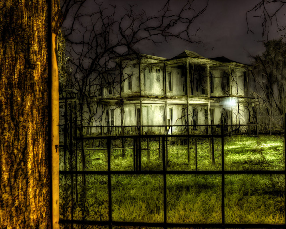 Abandoned two-story house at night with eerie lighting and metal fence