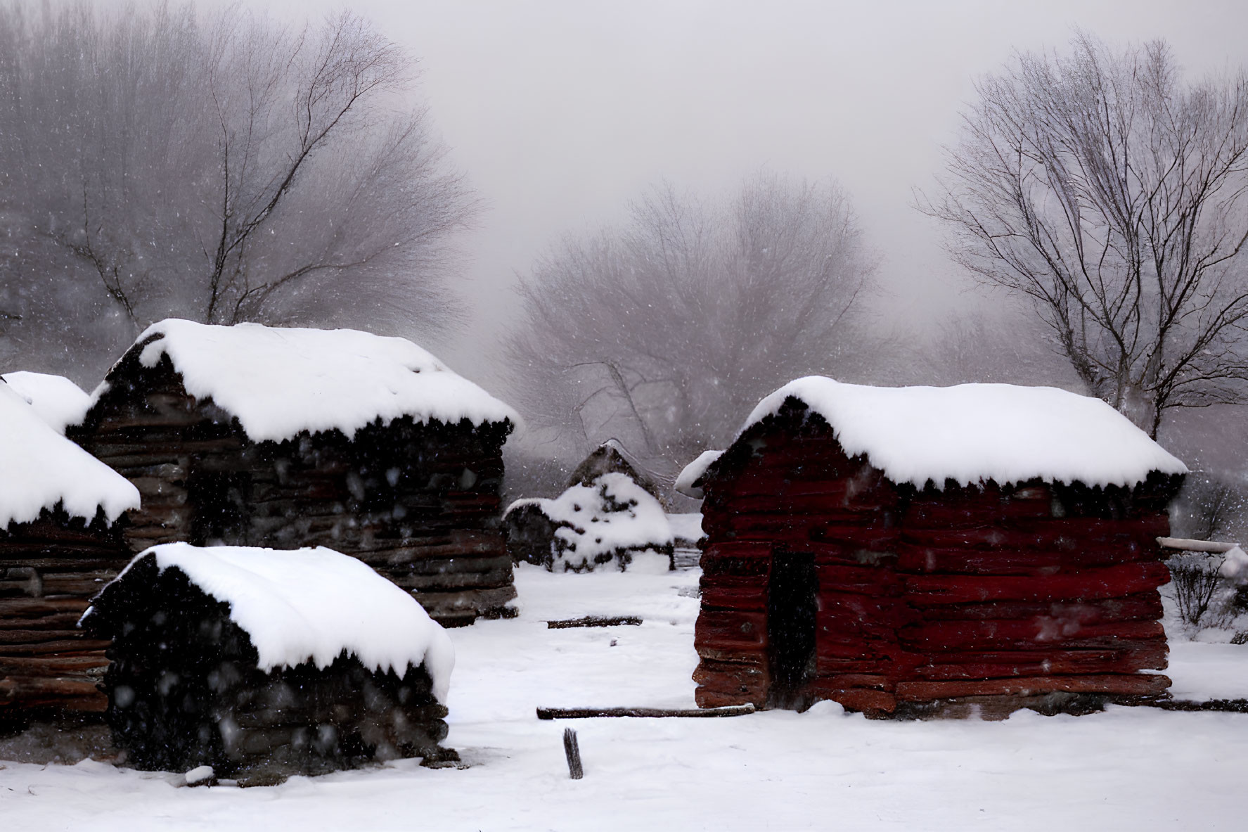 Winter scene: Snow-covered log cabins and leafless trees in fog.