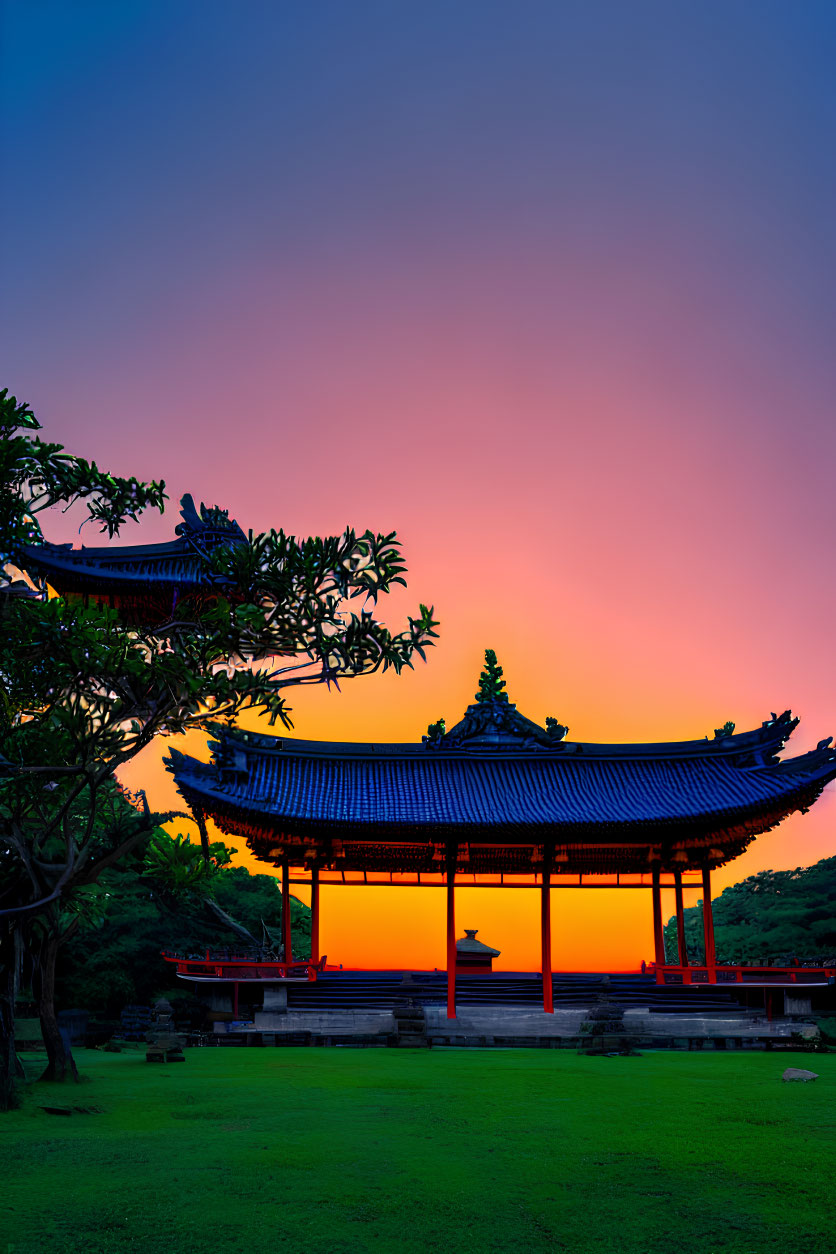 Colorful Asian-style pavilion at sunset with pink and orange hues and lush greenery