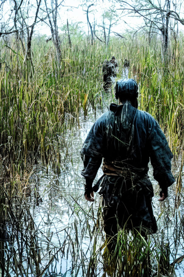 Group of people wading in marshy wetland with tall grasses