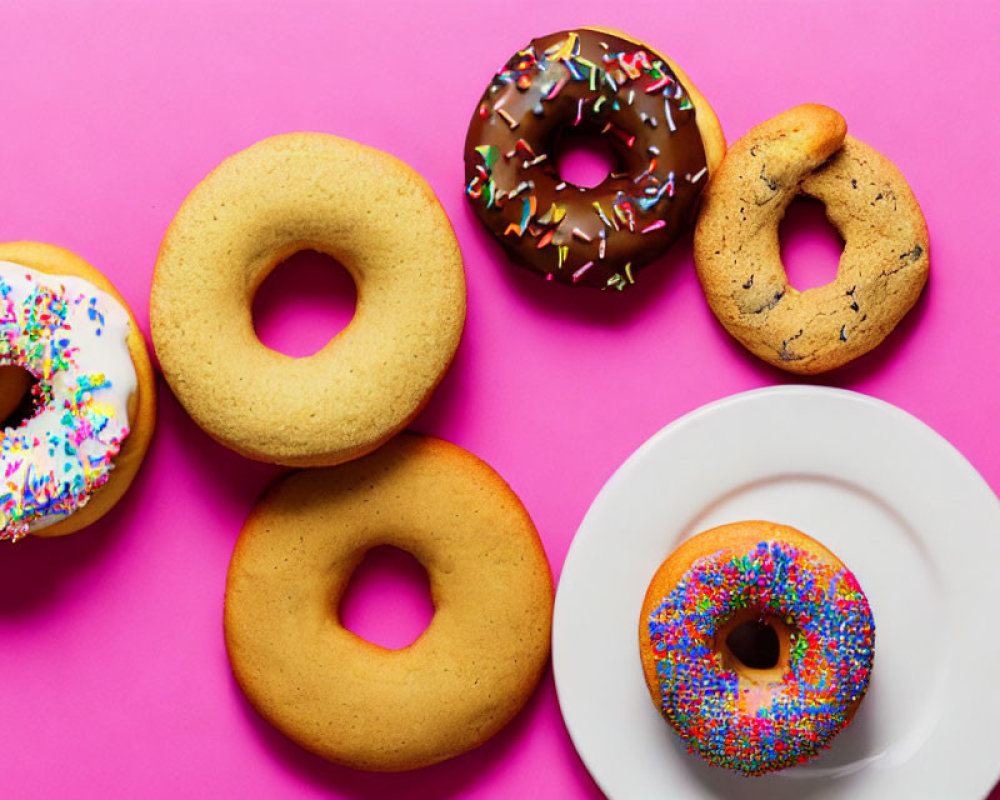 Assorted donuts on pink background with sprinkles and chocolate glaze