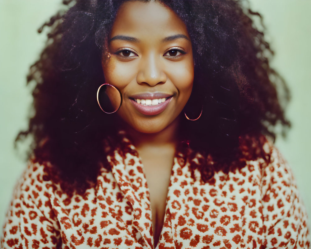 Smiling woman with curly hair in leopard print top on green background