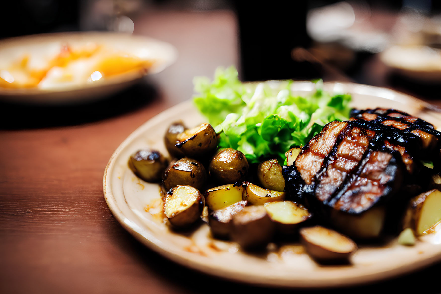 Sear-marked grilled steak with roasted potatoes and lettuce plate.