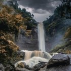 Tranquil waterfall in lush forest with pink blossoms