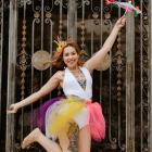 Dark-Haired Woman in Lacy Dress Surrounded by Colorful Flowers at Ornate Black Gate