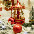 Miniature Christmas village scene with carousel, snow-covered trees, streetlamps, and reindeer.