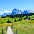 Scenic golf course watercolor with colorful flowers, green hills, trees, and mountains.