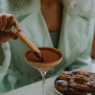 Cream-suited person lighting cigar over chocolate cocktail in elegant bar setting