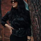 Long black hair woman in sequined dress with sunglasses against multicolored bokeh.