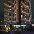 Night cityscape with neon-lit skyscrapers and reflection of traditional building in water