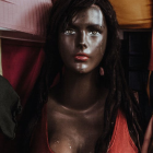 Portrait of woman with blue eyes, neon face paint, pirate hat, black curly hair.