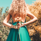 Woman standing in blooming garden with flower, sunlit hair, and colorful dress