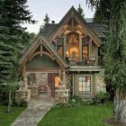 Charming two-story forest cottage with glowing windows and cobblestone path