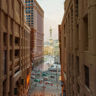 Vibrant urban street at sunset with high-rise buildings, traffic, and pedestrians