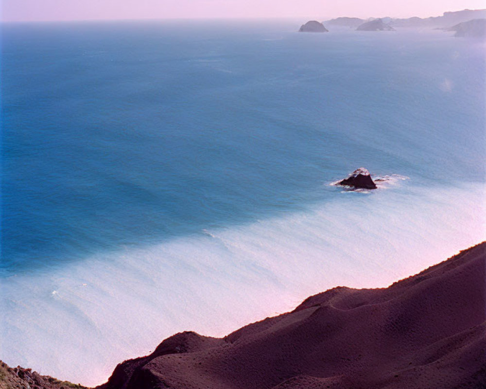 Scenic coastal road descending mountain slope by serene ocean and distant islet