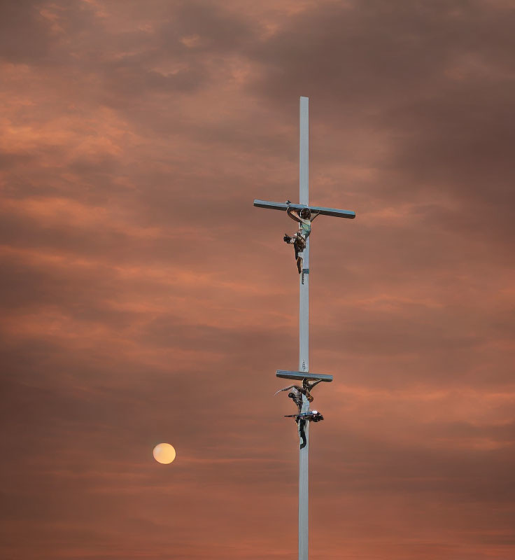 Crucifixes on pole under orange sunset sky with moon view