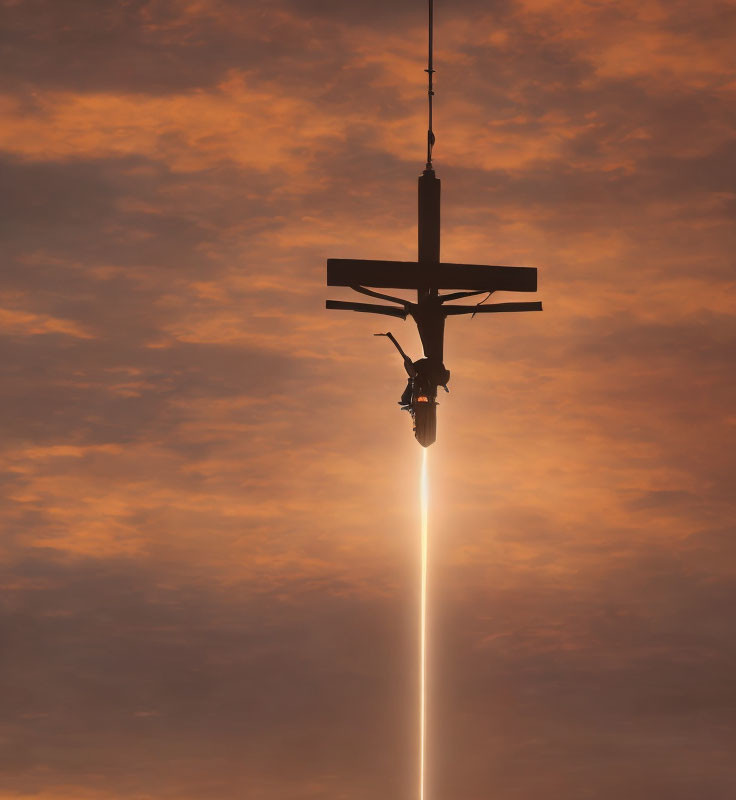 Person hanging from cross-like structure under bright sun against orange sky