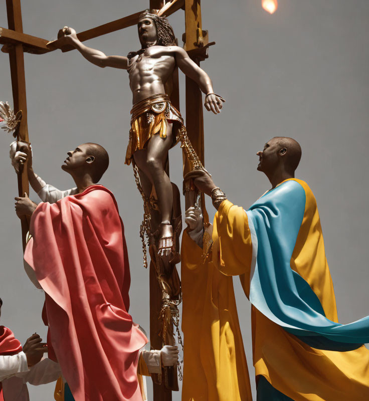 Religious statue of Jesus on the cross with two figures in colorful robes