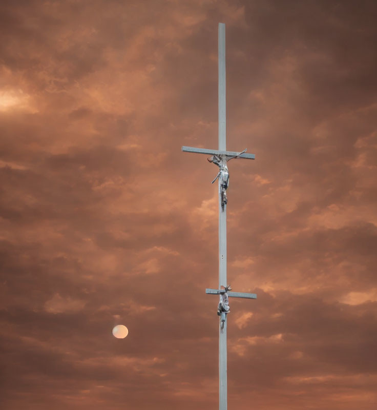 Crucifix against dramatic orange sky with sun and clouds