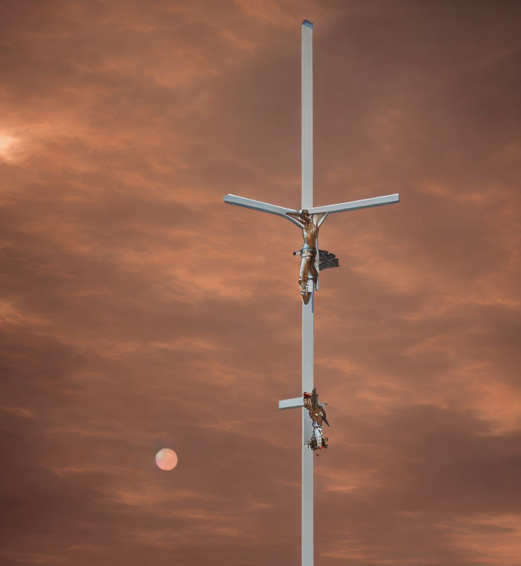 Crucifix with figures ascending against cloudy orange sky