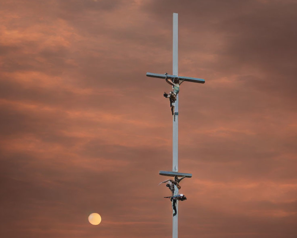 Crucifixes on pole under orange sunset sky with moon view