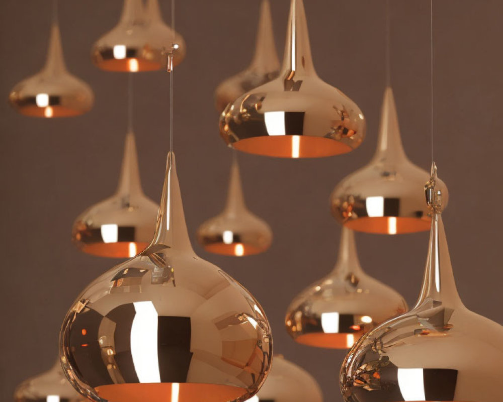 Reflective copper-toned pendant lights at varying heights on neutral backdrop