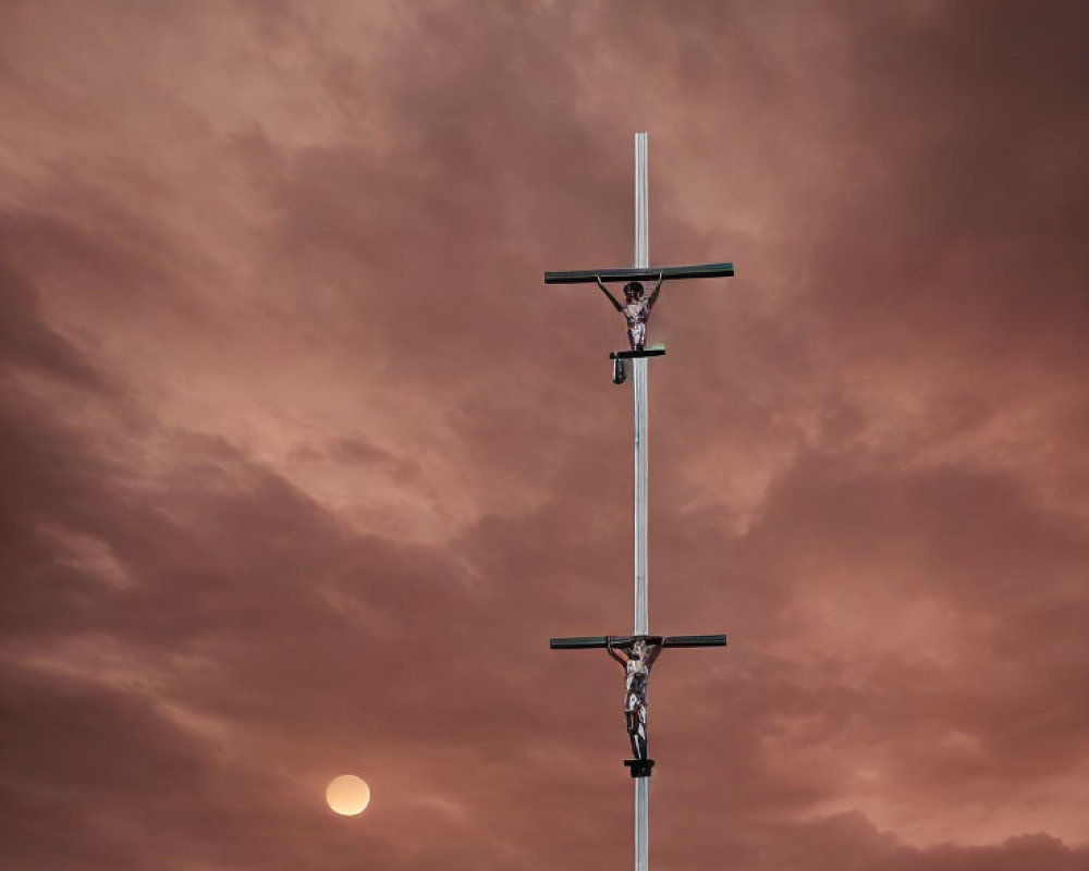 Religious cross with figures on dramatic orange sky and sun.