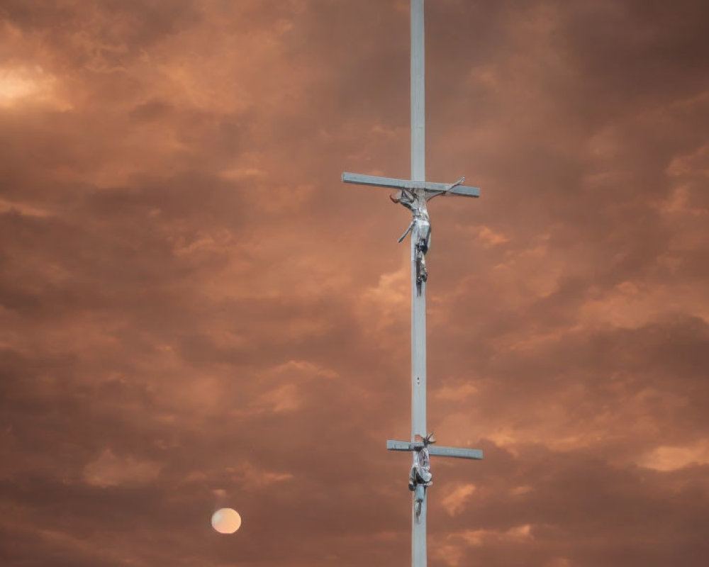 Crucifix against dramatic orange sky with sun and clouds